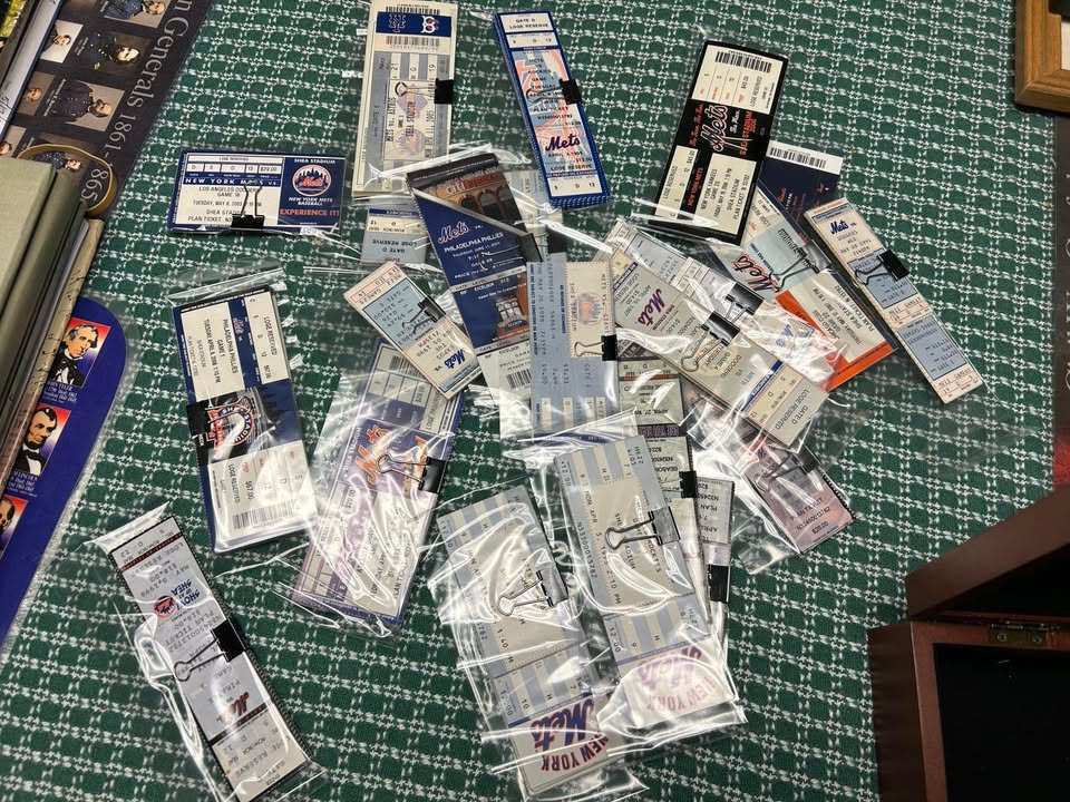 Dozens of New York Mets tickets in clear sleeves spread across a table